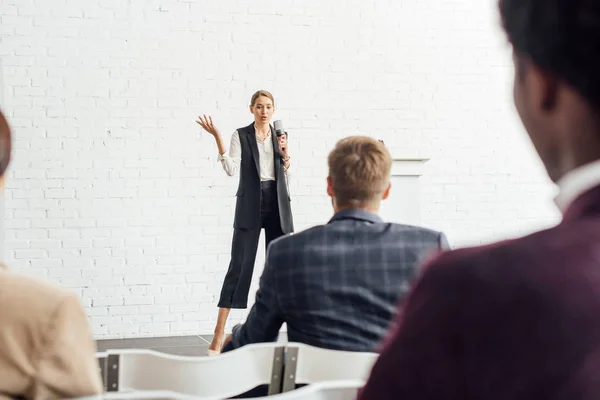 Attraktive Geschäftsfrau hält Mikrofon in der Hand und spricht während der Konferenz im Konferenzsaal — Stockfoto