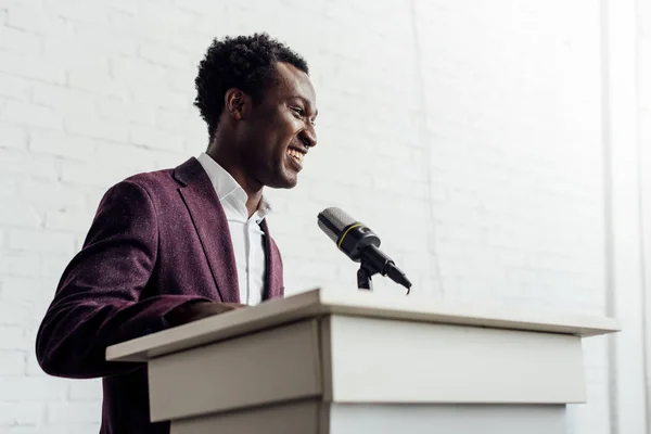 Hombre de negocios afroamericano en ropa formal sonriendo durante la conferencia - foto de stock