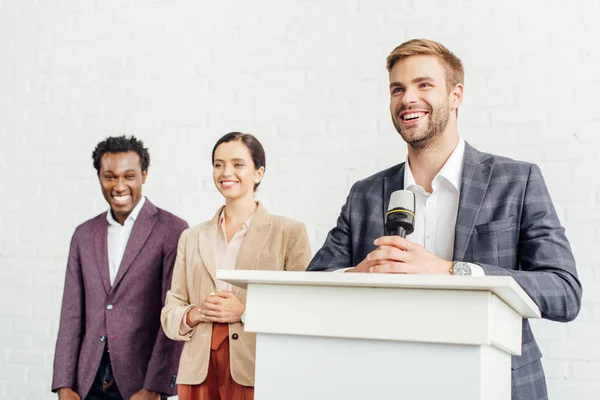 Lächelnder Geschäftsmann in formeller Kleidung spricht während der Konferenz im Konferenzsaal — Stockfoto