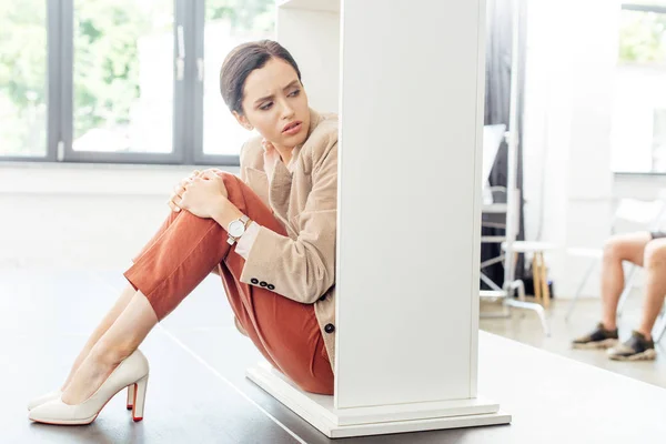 Attraktive und verängstigte Geschäftsfrau in festlicher Kleidung auf dem Boden sitzend — Stockfoto