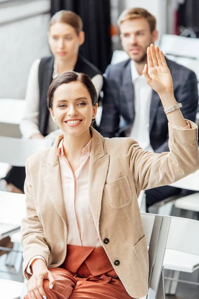 Foyer sélectif de la femme attrayante dans l'usure formelle levant la main pendant la conférence — Photo de stock