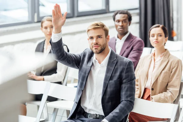 Selective focus of businessman raising hand during conference in conference hall — Stock Photo