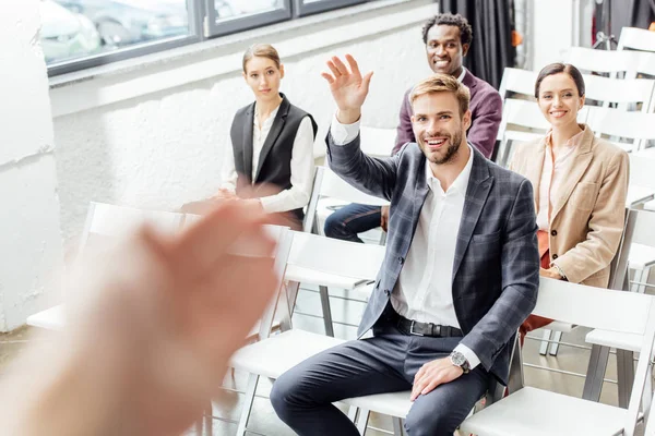 Selektiver Fokus des Geschäftsmannes, der während der Konferenz die Hand hebt und lächelt — Stockfoto