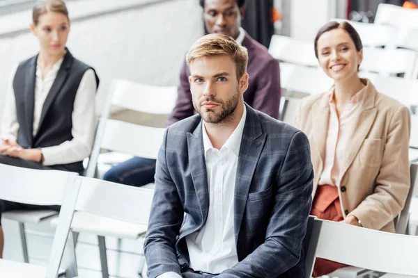 Selective focus of businessman in formal wear sitting during conference — Stock Photo