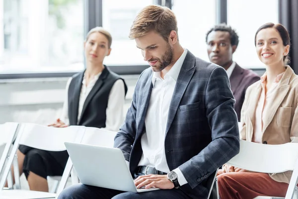 Enfoque selectivo del hombre de negocios en el desgaste formal utilizando el ordenador portátil durante la conferencia - foto de stock