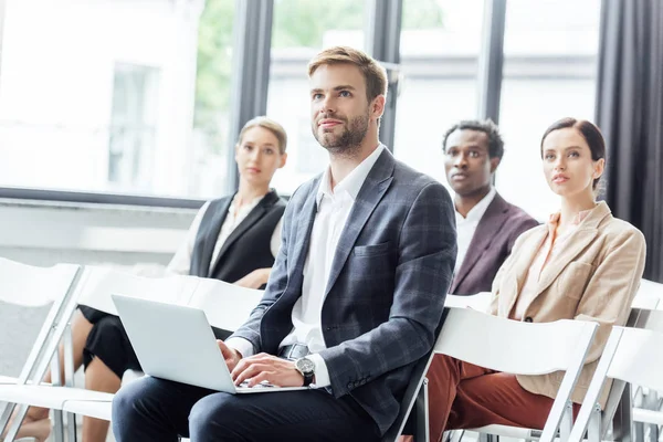 Selective focus of businessman in formal wear holding laptop during conference — Stock Photo