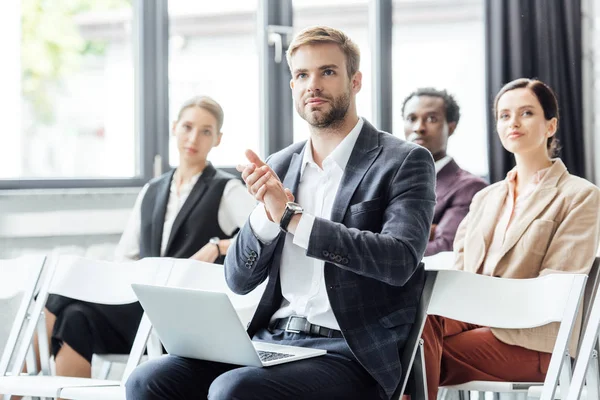 Selective focus of businessman in formal wear holding laptop and clapping during conference — Stock Photo