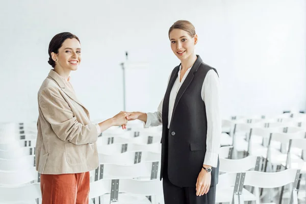 Двое привлекательных коллег в формальной одежде пожимают руки в конференц-зале — стоковое фото
