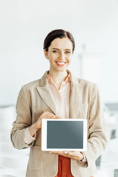 Приваблива бізнес-леді в офіційному одязі посміхається і тримає цифровий планшет — стокове фото