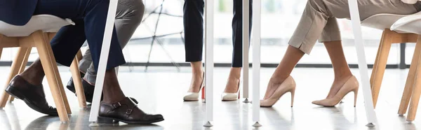 Panoramic shot of multiethnic businesspeople in formal wear sitting in office — Stock Photo