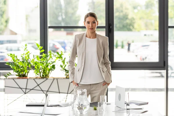 Attraktive Geschäftsfrau in formeller Kleidung blickt im Büro in die Kamera — Stockfoto