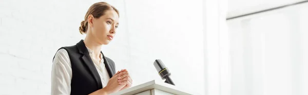 Prise de vue panoramique d'une femme d'affaires attrayante debout et parlant pendant la conférence au bureau — Photo de stock