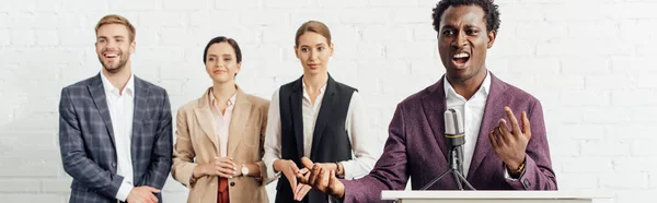 Tiro panorâmico de empresário afro-americano em desgaste formal falando durante conferência — Fotografia de Stock