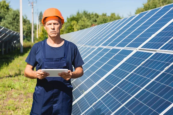 Gut aussehender Ingenieur in Overalls und Hardhat mit digitalem Tablet — Stockfoto