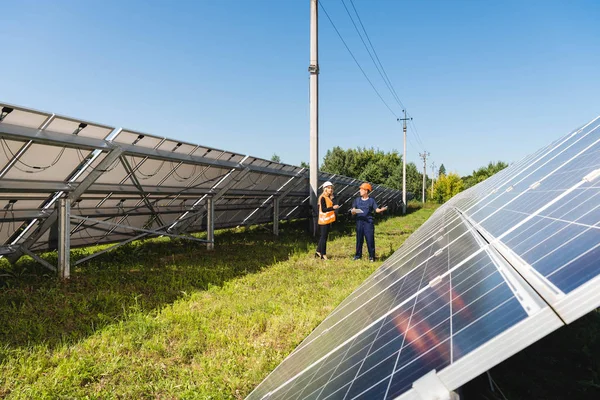 Engenheiro e empresária falando e andando perto de baterias de energia solar — Fotografia de Stock