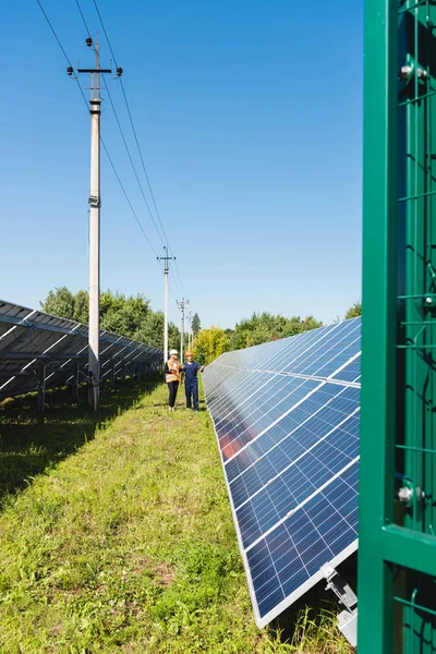 Ingeniero y mujer de negocios hablando y caminando cerca de baterías de energía solar - foto de stock