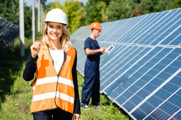 Attractive businesswoman in hardhat smiling and showing idea gesture — Stock Photo