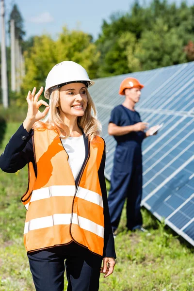 Attractive businesswoman in hardhat smiling and showing ok gesture — Stock Photo