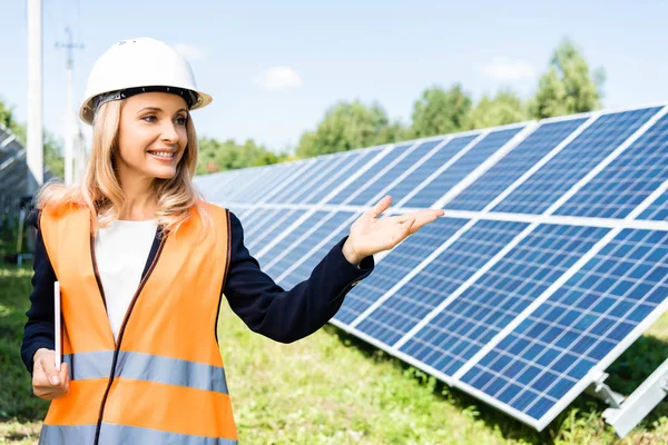 Attractive businesswoman in hardhat holding digital tablet and pointing with hand — Stock Photo