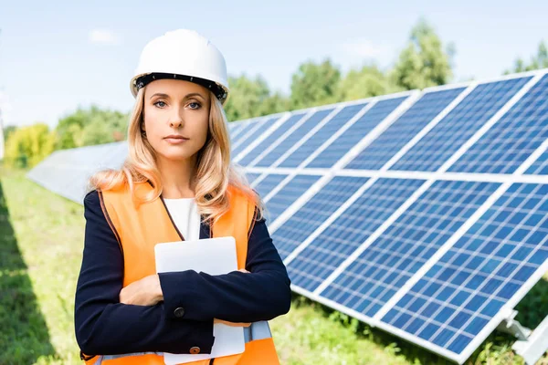 Attractive businesswoman in hardhat and safety vest holding digital tablet — Stock Photo