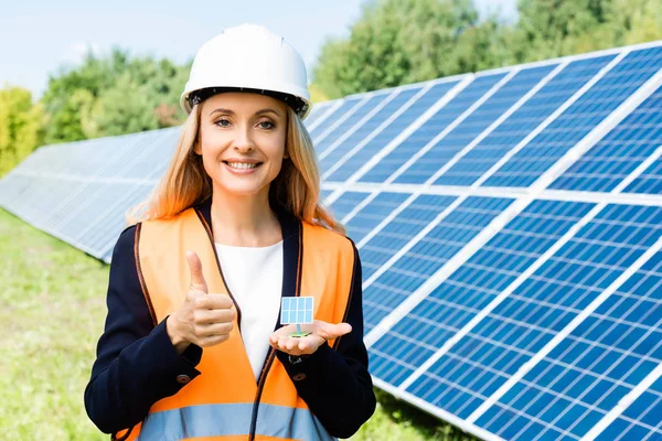 Plano panorámico de mujer de negocios en chaleco de seguridad celebración de modelo de batería solar - foto de stock