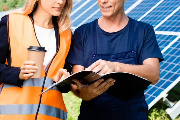 Vista recortada de ingeniero y mujer de negocios hablando y sosteniendo carpeta - foto de stock