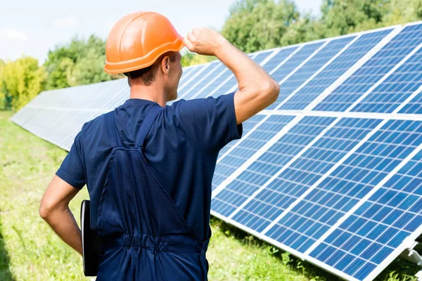 Back view of engineer in t-shirt and orange hardhat holding folder — Stock Photo