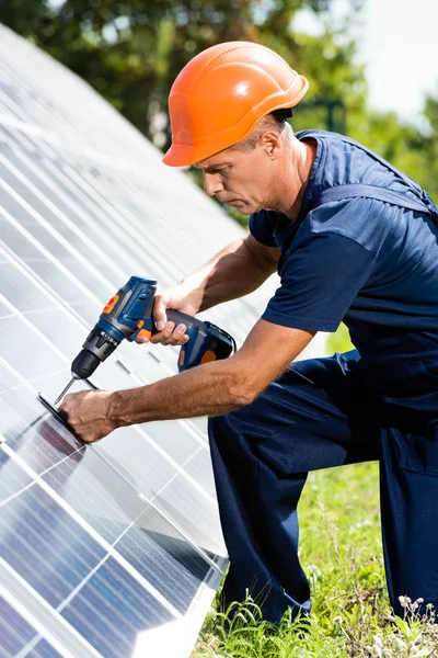 Engenheiro bonito em t-shirt e hardhat laranja usando broca — Fotografia de Stock