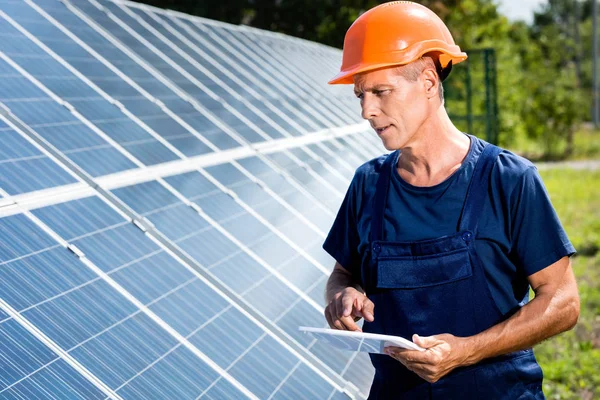 Handsome engineer in t-shirt and orange hardhat holding digital tablet — Stock Photo