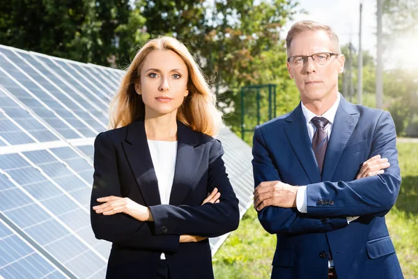 Handsome businessman and attractive businesswoman with crossed arms outside — Stock Photo