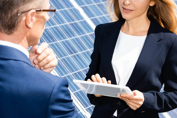 Cropped view of businessman and businesswoman talking and holding digital tablet — Stock Photo