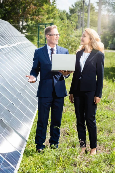 Bel homme d'affaires et attrayant femme d'affaires souriant et tenant ordinateur portable — Photo de stock