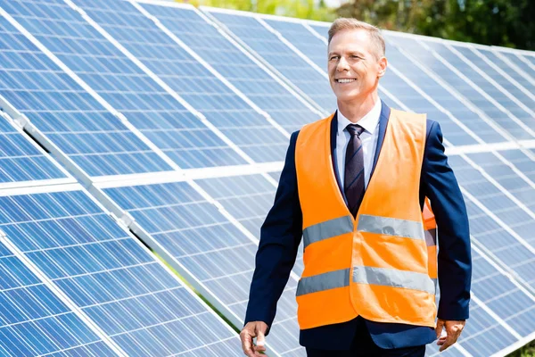 Bell'uomo d'affari in giubbotto di sicurezza sorridente e guardando altrove — Foto stock