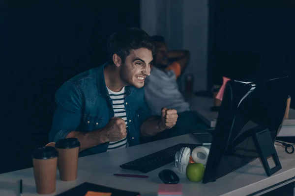 Wütender Programmierer gestikuliert, während er nachts im Büro in der Nähe eines amerikanischen Kollegen arbeitet — Stockfoto