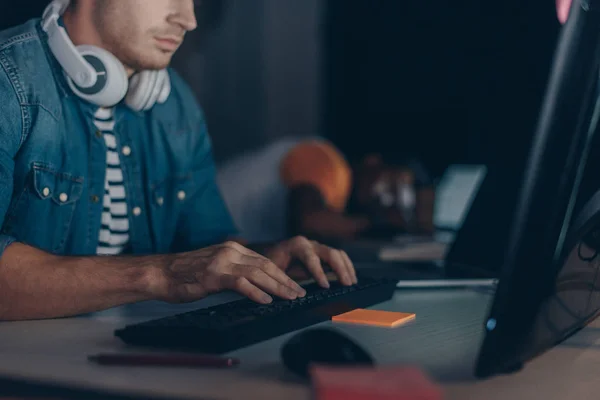 Vue recadrée du jeune programmeur travaillant près d'un collègue afro-américain dormant sur le lieu de travail — Photo de stock