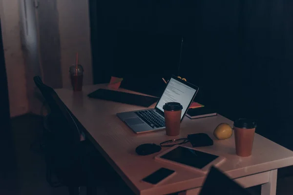 Desk with laptop, digital tablet, smartphone, coffee to go and glass of juice — Stock Photo