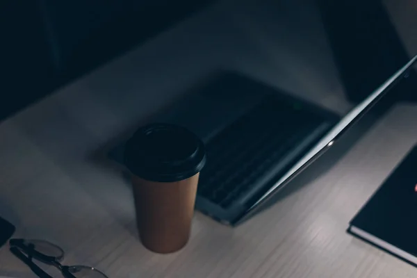 Escritorio con portátil y café para ir por la noche en la oficina - foto de stock