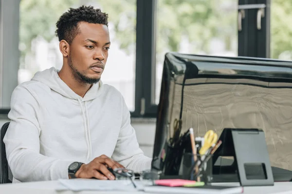 Joven programador afroamericano que trabaja en la computadora en la oficina — Stock Photo