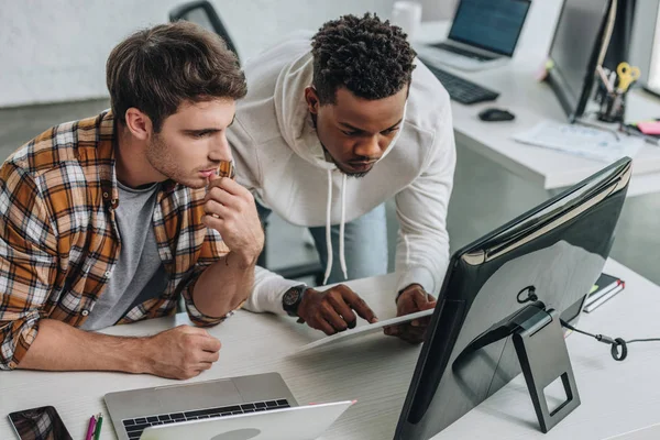 Dos programadores multiculturales serios que trabajan juntos en la oficina - foto de stock