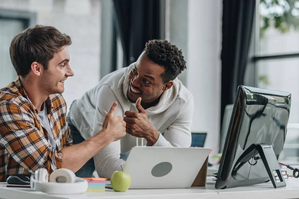 Two happy multicultural programmers looking at each other and showing thumbs up — Stock Photo