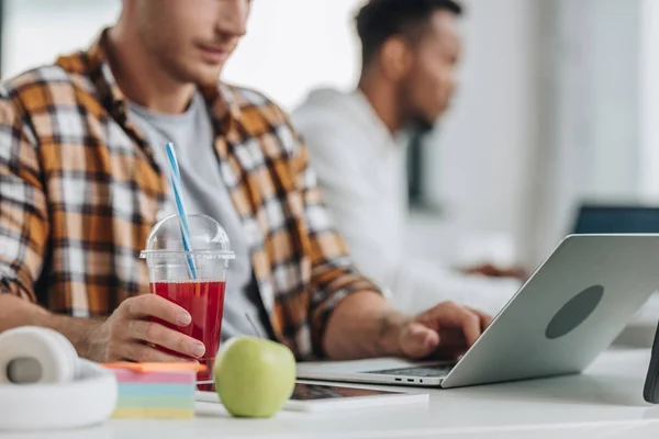 Vue recadrée du programmeur travaillant à l'ordinateur portable tout en étant assis près d'un collègue afro-américain — Photo de stock