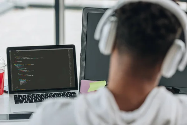Назад погляд афроамериканців програміста в навушниках працює на ноутбуці в офісі — стокове фото