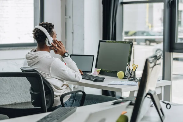 Foco seletivo do programador afro-americano sentado no local de trabalho em fones de ouvido — Fotografia de Stock