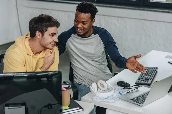 Fröhlich afrikanisch-amerikanischer Programmierer zeigt auf Computermonitor, während er neben Kollege sitzt — Stockfoto