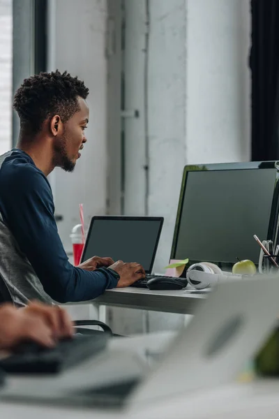 Joven programador afroamericano que trabaja en la oficina cerca de colega - foto de stock