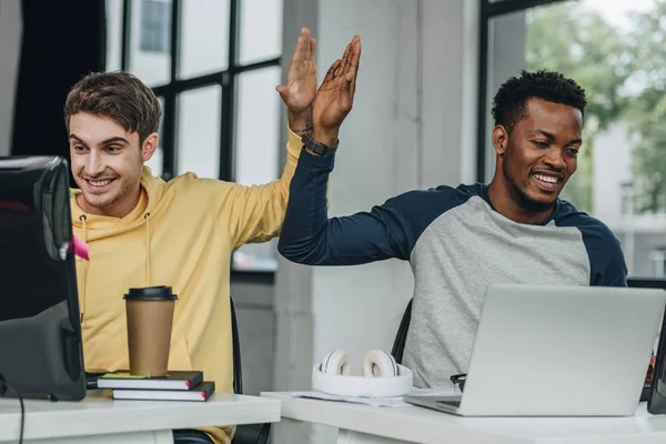 Happy multicultural programmers giving high five while working in office together — Stock Photo