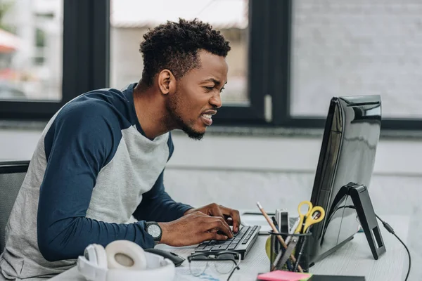 Aufmerksame afrikanisch-amerikanische Programmiererin arbeitet am Computer im Büro — Stockfoto