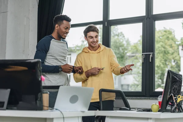 Lächelnde multikulturelle Programmierer, die gemeinsam auf den Computermonitor schauen — Stockfoto