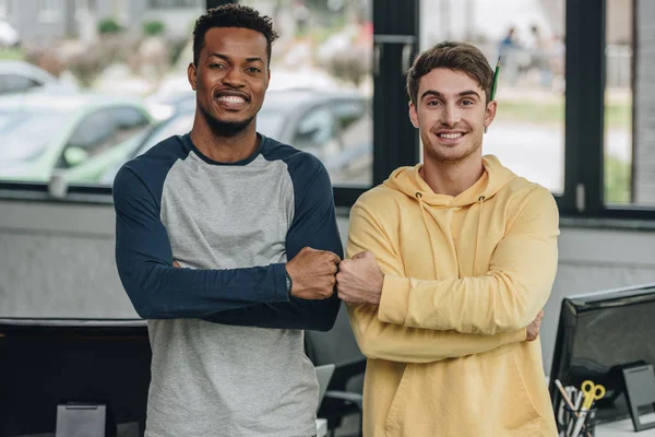 Two happy multicultural programmers smiling at camera in office — Stock Photo