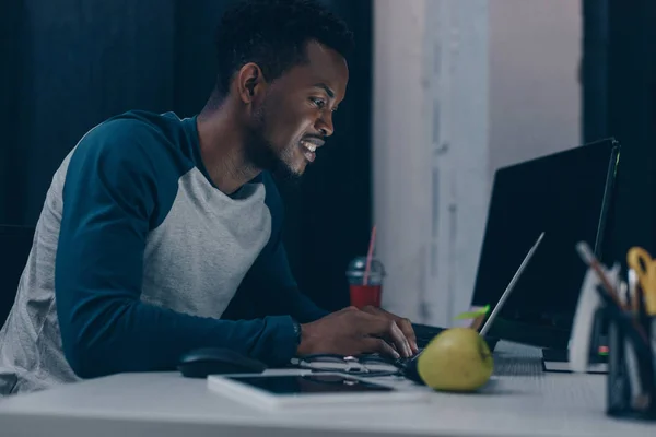 Alegre afroamericano programador trabajando en la noche en la oficina - foto de stock